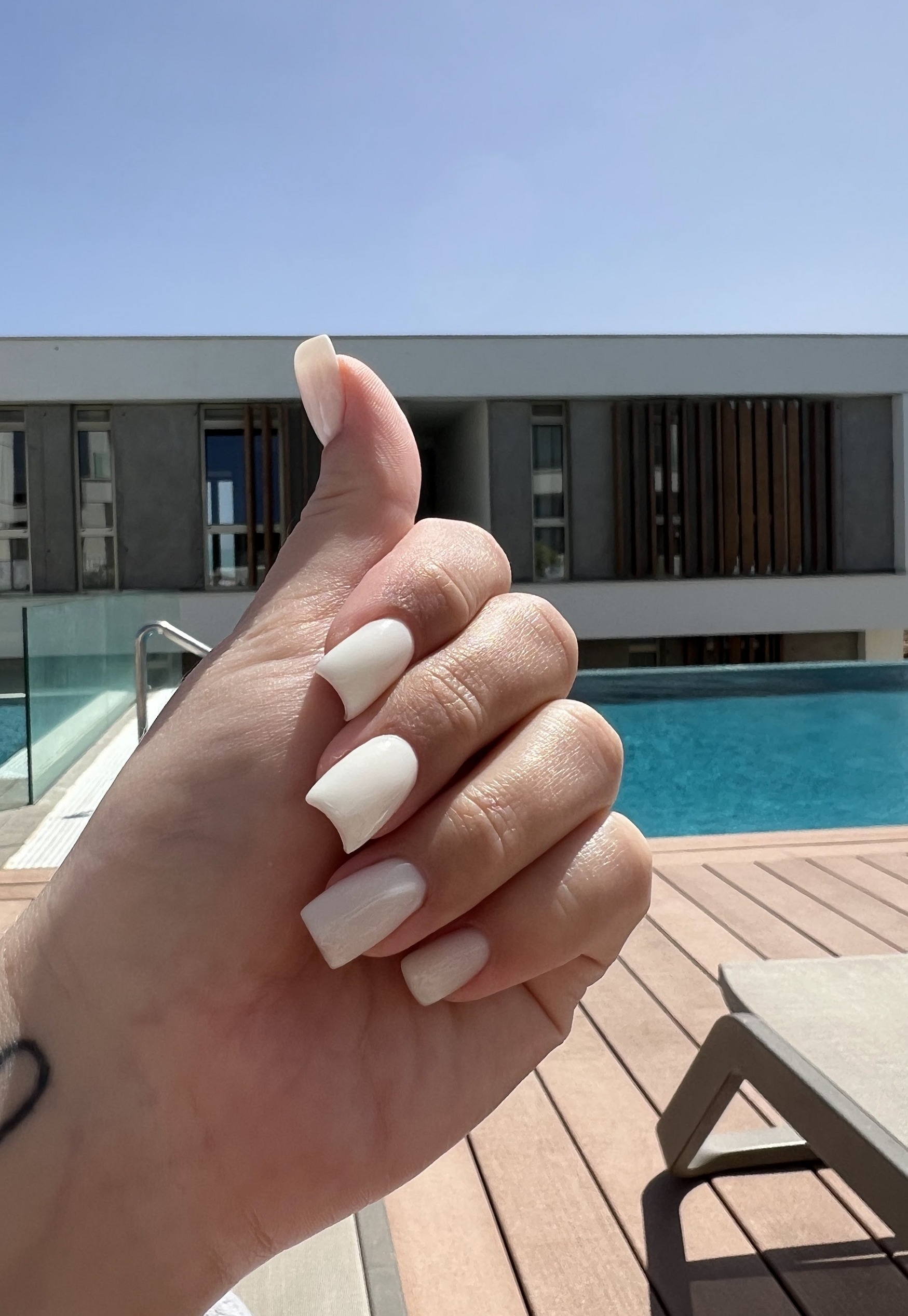 Melkwitte korte nagels, gefotografeerd op vakantie bij een zwembad